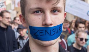 Teenaged man with taped mouth protesting censorship at demonstration against a new copyright law by European Union, "Artikel 13." Erfurt, Germany. 23 March 2019. Editorial credit:  Timo Nausch / Shutterstock.com