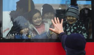 Children fleeing from Ukraine are seen in a bus playing with a Polish policeman after crossing Ukrainian-Polish border