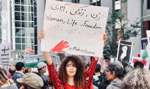 Woman Holding protest sign reading "women, life, freedom"