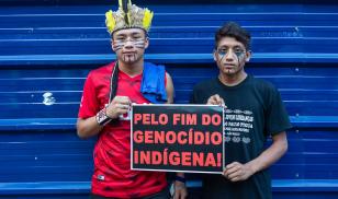 Two young indigenous men protesting holding banner "Stop the indigenous genocide", in march for the rights of the indigenous people.  São Paulo, Brazil. 1 January 2019. Editorial Credit: PARALAXIS / Shutterstock.com