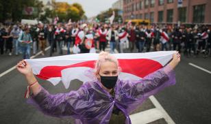 ​​​​​​​A protester carries a version of the Belarusian flag favored by the democratic opposition during a demonstration in Minsk against the fraudulent August 2020 presidential election. Image credit: Sergei Bobylev\TASS via Getty Images.