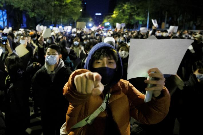 People hold white sheets of paper in protest over coronavirus disease (COVID-19) restrictions, after a vigil for the victims of a fire in Urumqi, as outbreaks of COVID-19 continue, in Beijing, China,