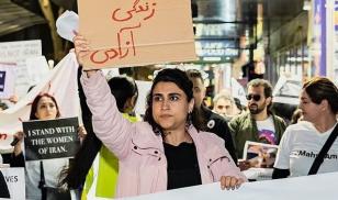 Woman Holds Protest Sign that reads "women, life, freedom" in Farsi