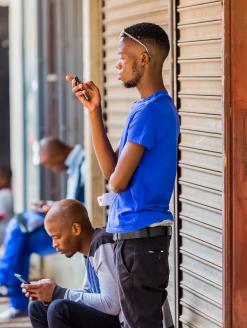 Men using their mobile phones on a sidewalk. Johannesburg, South Africa. Editorial credit:  Sunshine Seeds / Shutterstock.com 