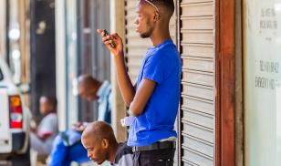Men using their mobile phones on a sidewalk. Johannesburg, South Africa. Editorial credit:  Sunshine Seeds / Shutterstock.com 